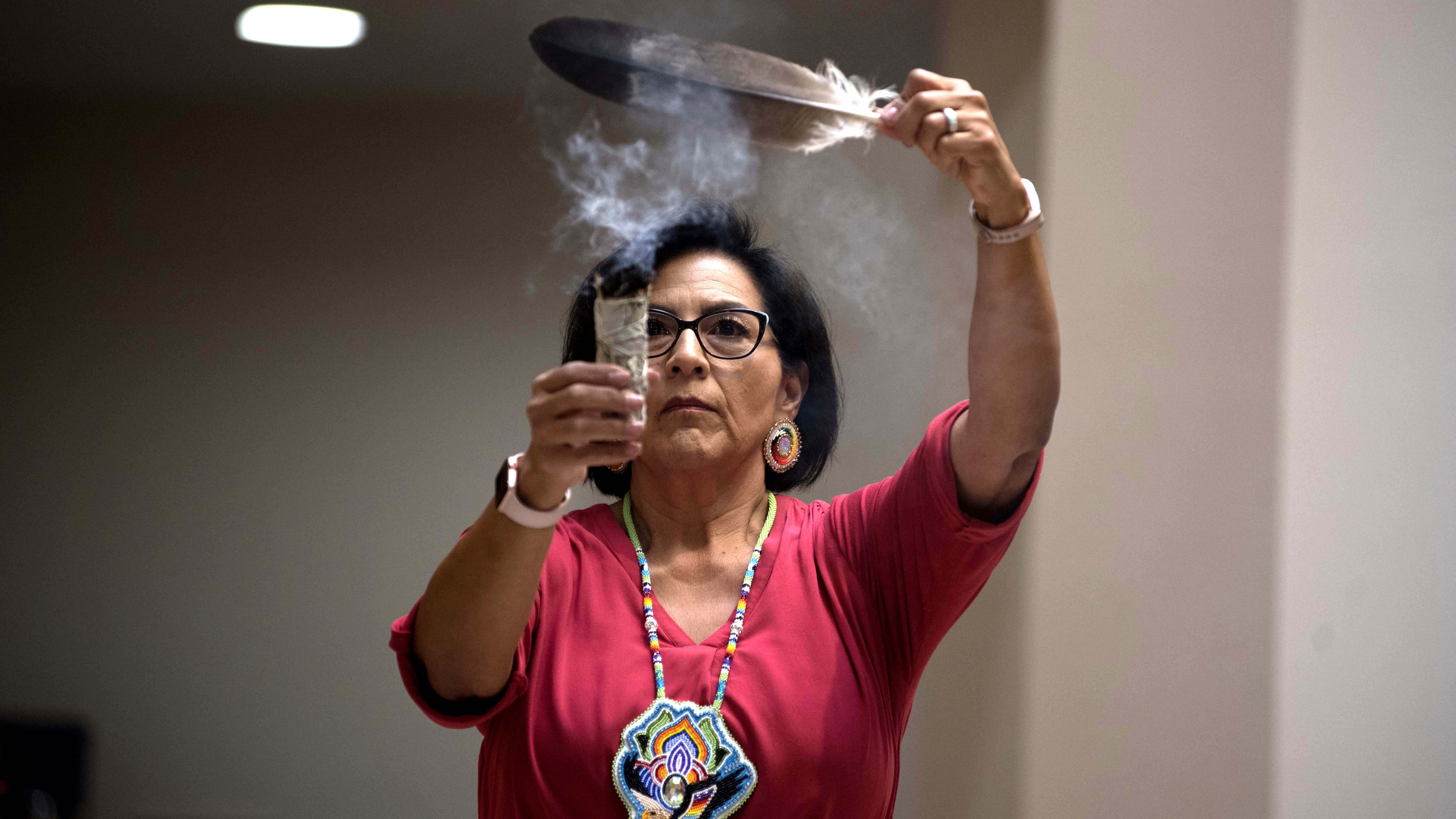 A member of the Native American community performs a smudging blessing.