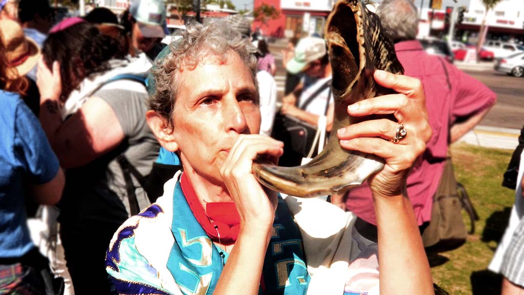 Rabbi Shifrah Tobacman, a healthy housing program manager i the San Francisco Bay Area, blows a Shofar before the rally and march.