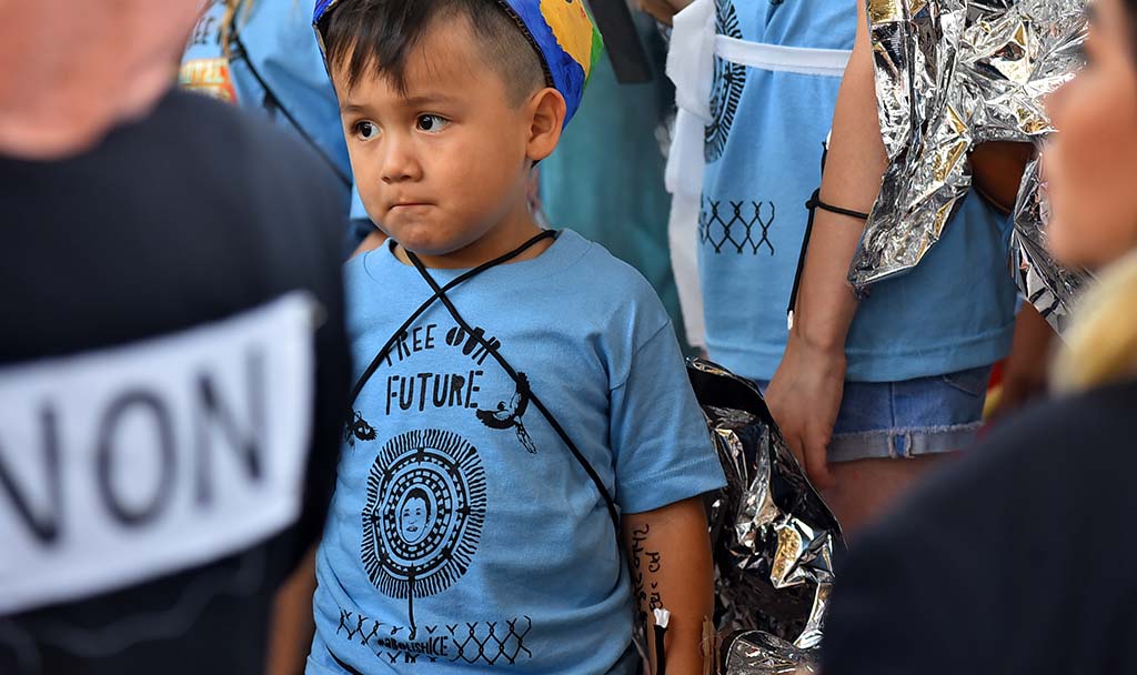A young marcher with phone numbers written on his arm waits for the beginning of the march.