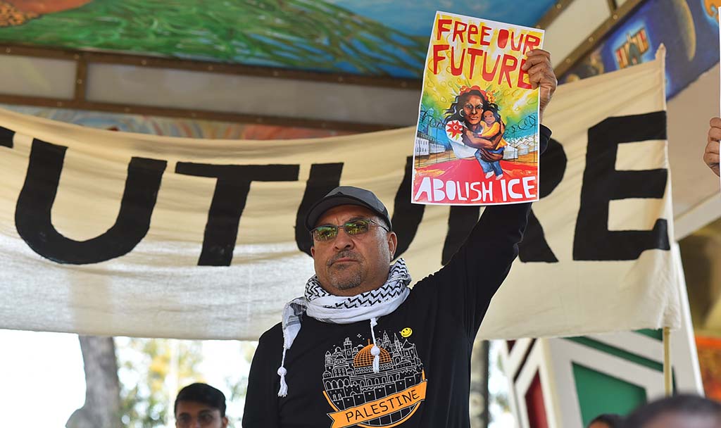 An activist displays the rally's poster at Chicano Park.