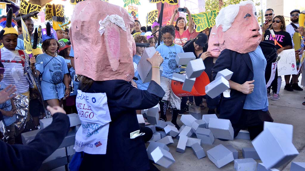 Children break through blocks that were set up in Chicano Park by effigies of Trump Administration officials.