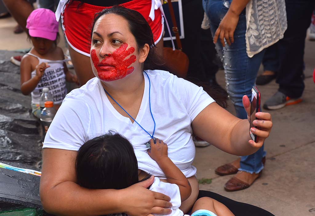 A woman held her child and a cell phone at the Free Our Future rally.