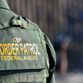 A Border Patrol agent is positioned by the border fence.