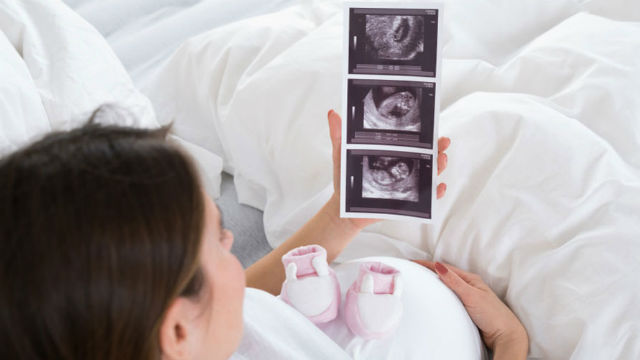 Pregnant woman looks at ultrasound images
