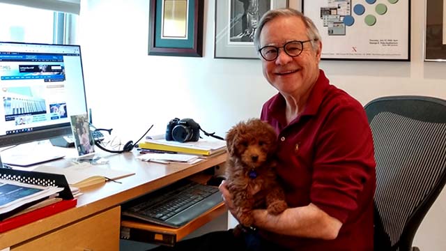 Times of San Diego editor and publisher Chris Jennewein at his home office holds Razzleberry, the family's new Miniature Goldendoodle puppy.